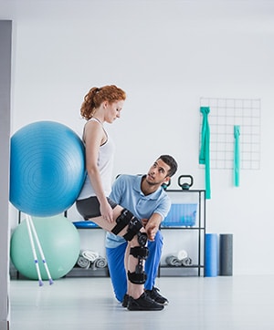 Woman with a knee brace works with her physical therapist to get better